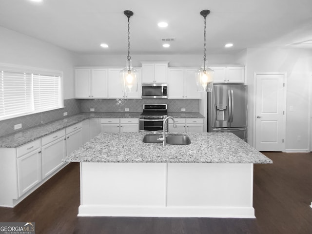 kitchen with visible vents, dark wood-style floors, a kitchen island with sink, stainless steel appliances, and a sink