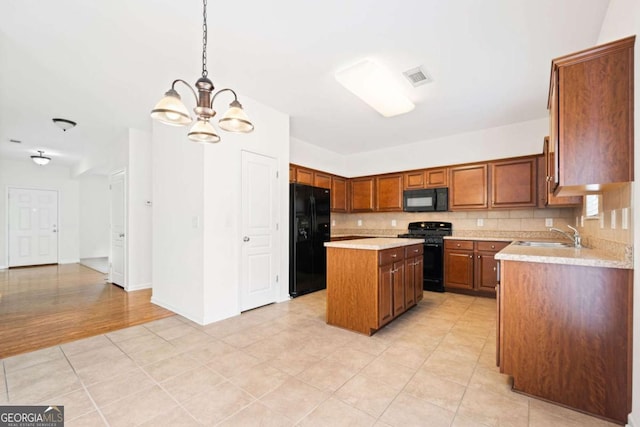 kitchen with a sink, visible vents, light countertops, backsplash, and black appliances