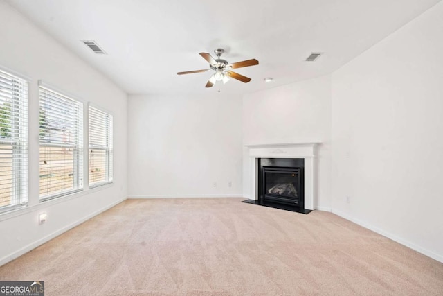 unfurnished living room featuring carpet, visible vents, baseboards, and a fireplace with flush hearth