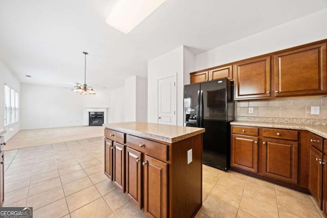 kitchen featuring light tile patterned floors, a kitchen island, backsplash, and black fridge