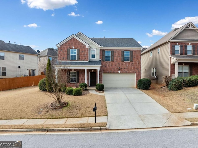 traditional-style home with brick siding, covered porch, an attached garage, fence, and driveway