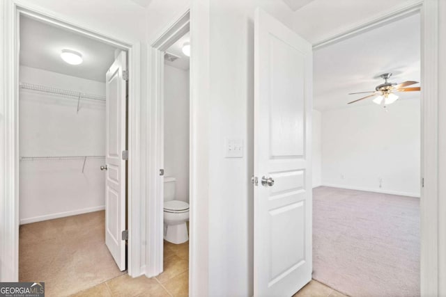 hall with light carpet and light tile patterned floors