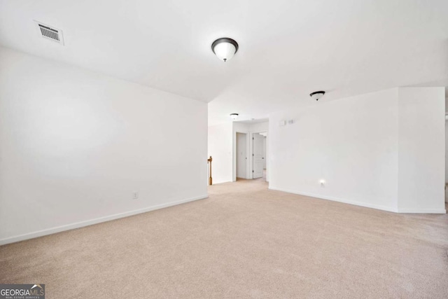 spare room with light carpet, visible vents, and baseboards