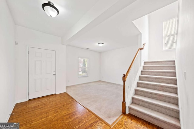 foyer entrance featuring stairs, wood finished floors, and baseboards