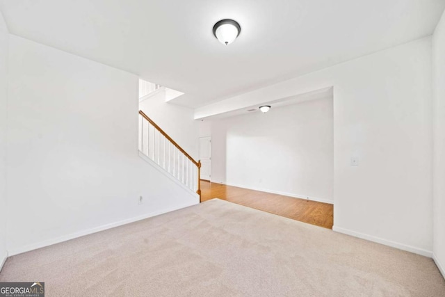 carpeted spare room with baseboards and stairs