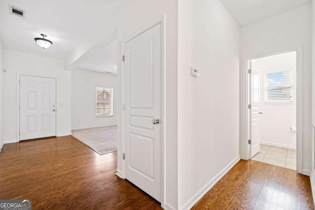 hall with visible vents, baseboards, and wood finished floors