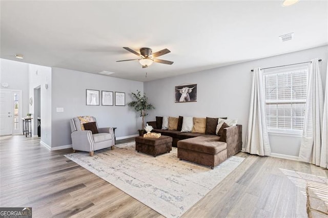 living area featuring ceiling fan, visible vents, light wood-type flooring, and baseboards