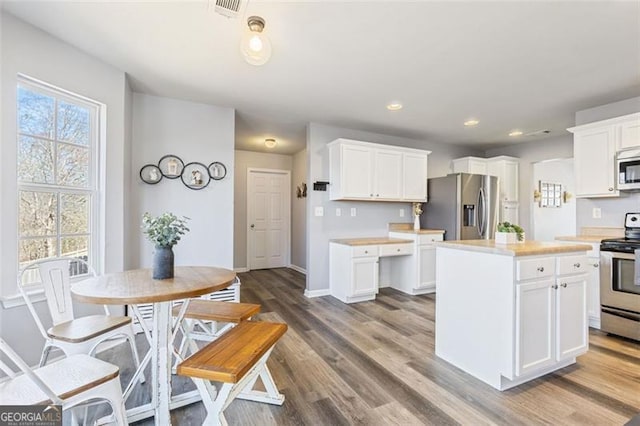 kitchen with visible vents, wood finished floors, white cabinetry, stainless steel appliances, and light countertops