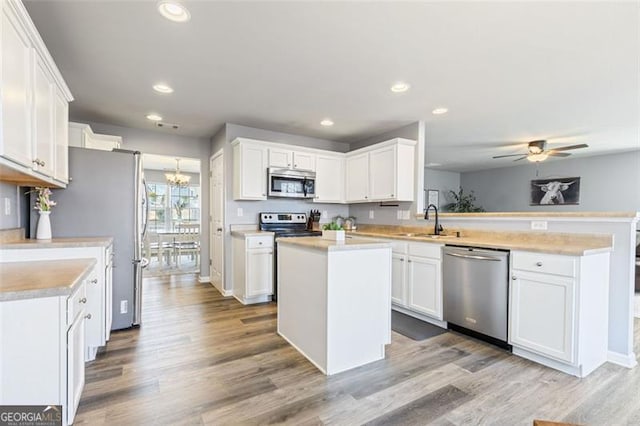 kitchen with white cabinets, a peninsula, stainless steel appliances, and a sink