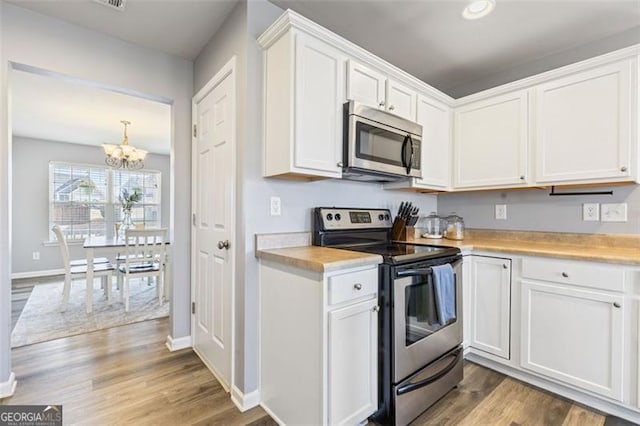 kitchen with appliances with stainless steel finishes, wood finished floors, white cabinets, and light countertops