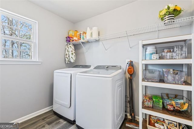 clothes washing area with laundry area, washing machine and dryer, dark wood-style flooring, and baseboards