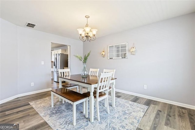 dining space featuring visible vents, wood finished floors, baseboards, and a chandelier