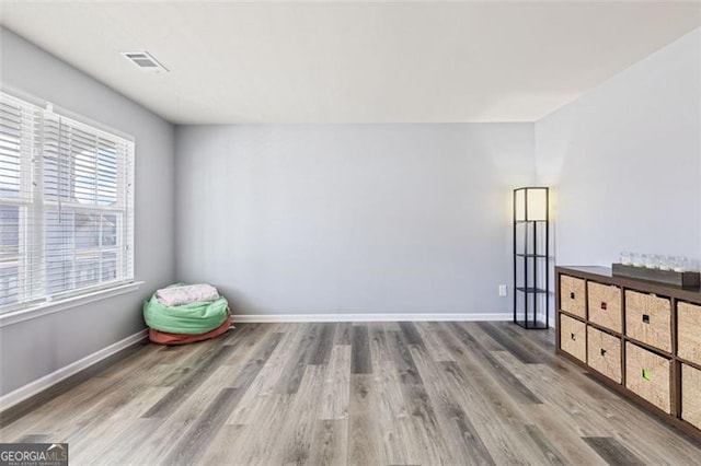 unfurnished room with visible vents, wood finished floors, and baseboards