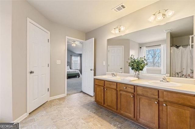 ensuite bathroom featuring a sink, visible vents, baseboards, and double vanity