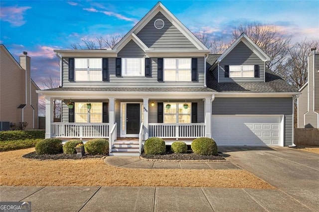 traditional-style home featuring driveway, a porch, a shingled roof, a garage, and central AC unit