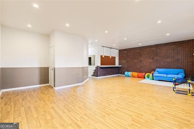 interior space featuring recessed lighting, brick wall, baseboards, and wood finished floors