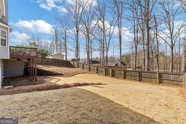 view of yard featuring a wooden deck, a fenced backyard, and stairs