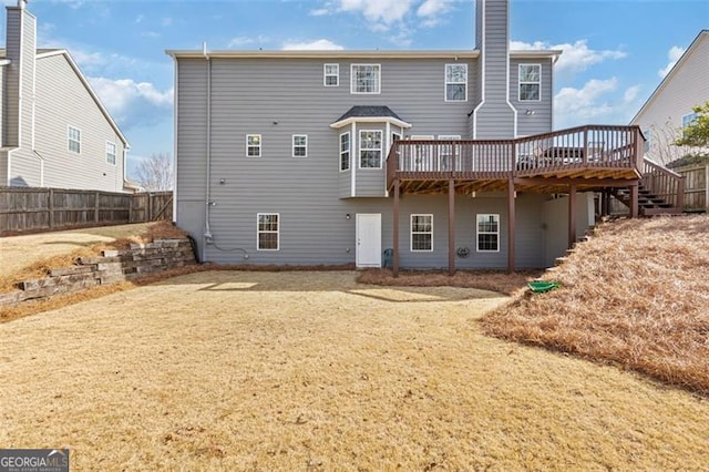 rear view of house featuring a wooden deck, a chimney, and fence