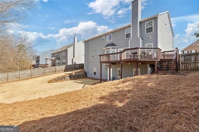 rear view of property featuring a deck, a chimney, a fenced backyard, and a residential view