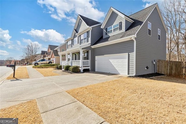 view of front of house featuring driveway, fence, a garage, and a residential view