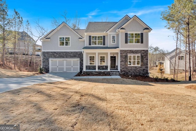 view of front of property with driveway, stone siding, an attached garage, and covered porch