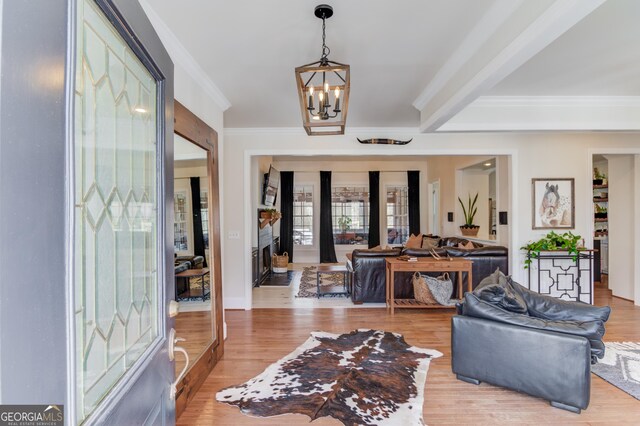 entryway featuring ornamental molding, light wood-type flooring, and an inviting chandelier