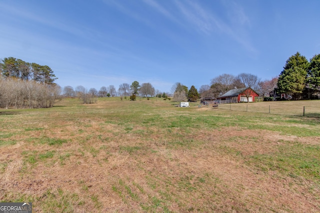 view of yard featuring an outbuilding, a rural view, and fence