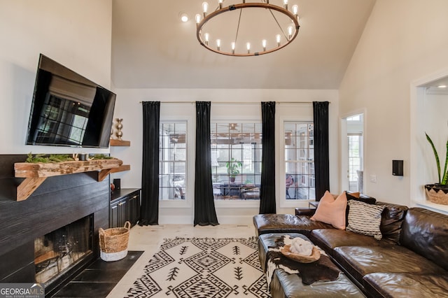 living area with high vaulted ceiling, a chandelier, a wealth of natural light, and a tile fireplace