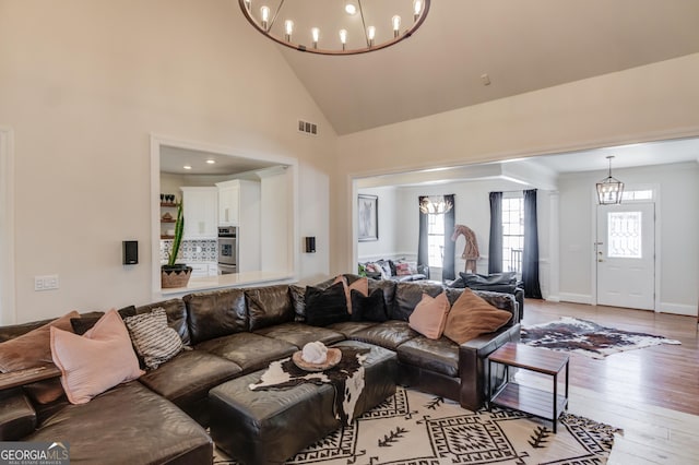 living area with a chandelier, light wood-style floors, visible vents, and a healthy amount of sunlight