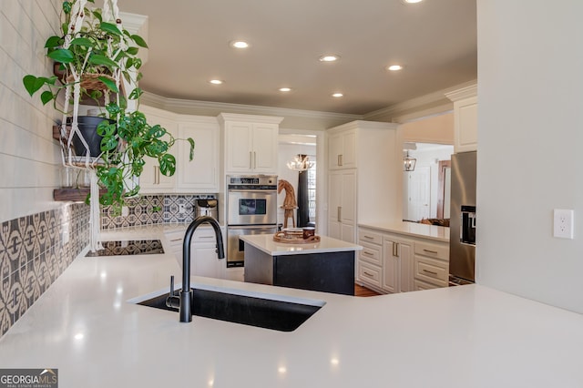 kitchen featuring stainless steel appliances, a sink, light countertops, ornamental molding, and decorative backsplash