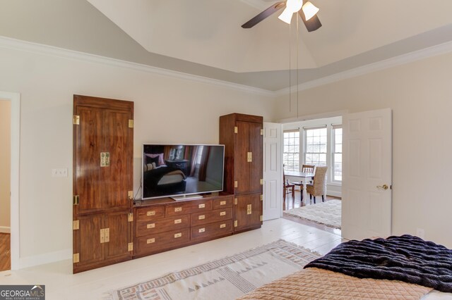 bedroom with crown molding, a raised ceiling, a ceiling fan, vaulted ceiling, and baseboards