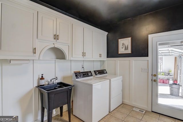 laundry area featuring light tile patterned floors, cabinet space, a decorative wall, visible vents, and washing machine and dryer