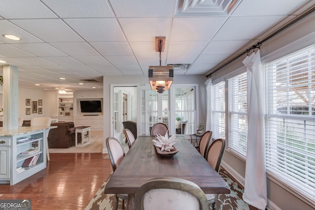 dining room featuring visible vents, ceiling fan, wood finished floors, a drop ceiling, and baseboards