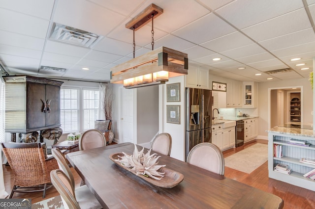 dining space with light wood-style floors, recessed lighting, visible vents, and a drop ceiling