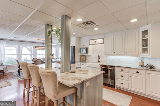 kitchen featuring stainless steel appliances, a sink, a kitchen bar, and light stone countertops