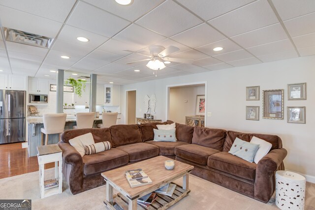 living room with ceiling fan, built in shelves, visible vents, and light colored carpet