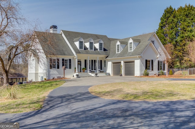 new england style home featuring roof with shingles, driveway, and a front lawn