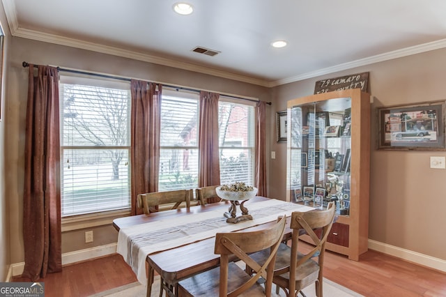 dining room with light wood-style floors, baseboards, visible vents, and ornamental molding