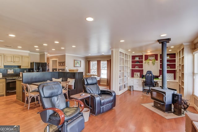 living area featuring a wood stove, light wood-style floors, ornamental molding, and recessed lighting