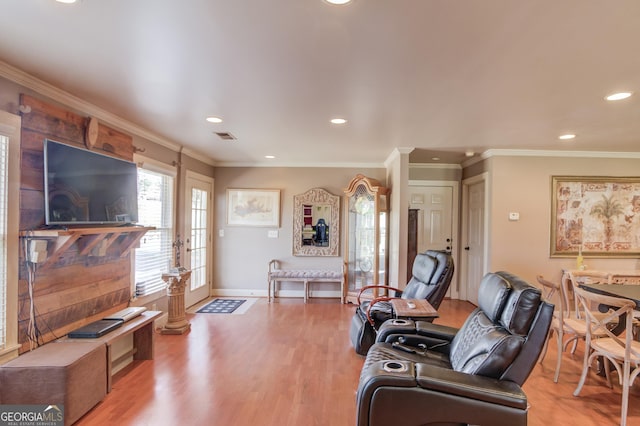 living area with ornamental molding, visible vents, and light wood finished floors