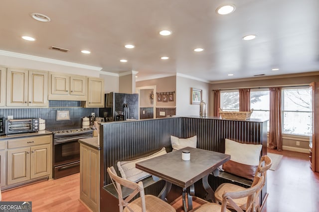 kitchen with a toaster, range with electric cooktop, cream cabinetry, black fridge, and light wood finished floors