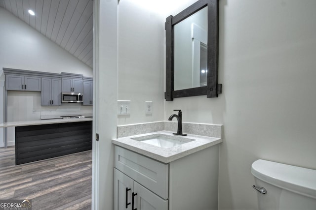 bathroom featuring tasteful backsplash, toilet, wood finished floors, vaulted ceiling, and vanity