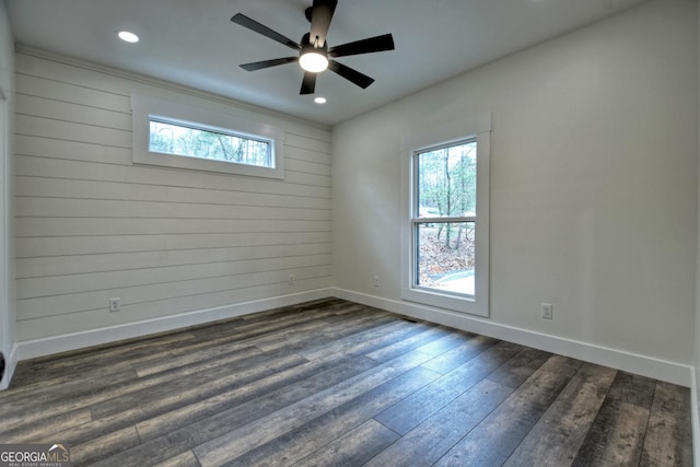 spare room with baseboards, dark wood finished floors, and a healthy amount of sunlight