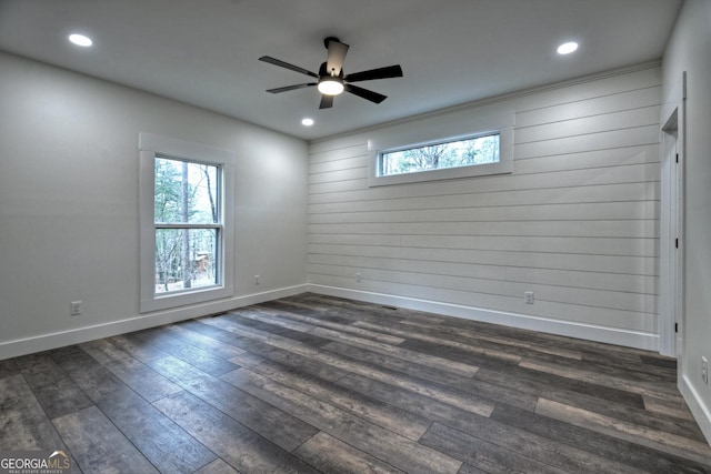 spare room with a healthy amount of sunlight, baseboards, and dark wood-type flooring