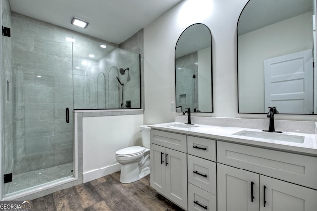 full bathroom with a sink, a shower stall, toilet, and wood finished floors