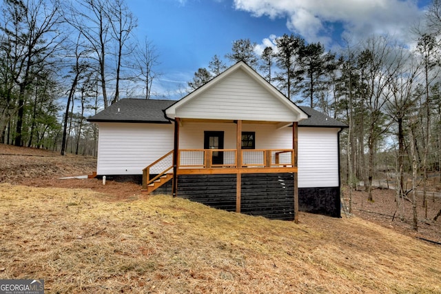 rear view of house featuring a wooden deck, stairs, and roof with shingles