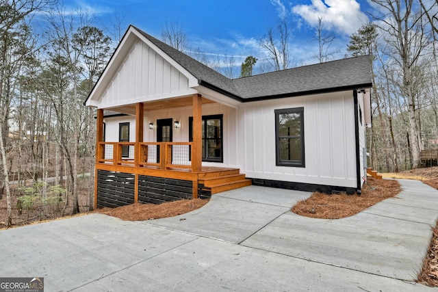 modern farmhouse featuring a porch, board and batten siding, and roof with shingles