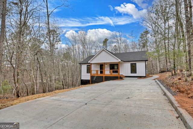 view of front of house featuring covered porch, concrete driveway, and roof with shingles