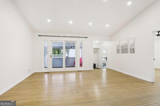 interior space with lofted ceiling, baseboards, light wood finished floors, and recessed lighting