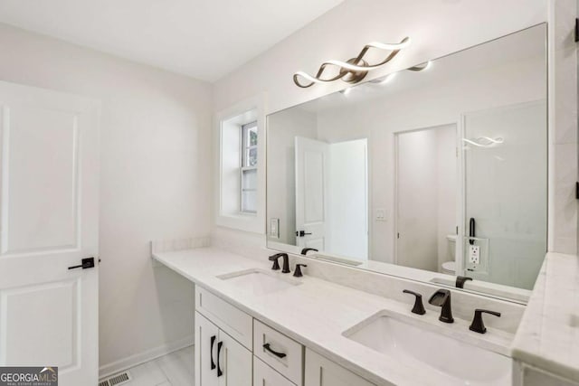 bathroom featuring double vanity, a shower stall, visible vents, and a sink